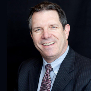 Man in suit and tie smiling with short brown hair
